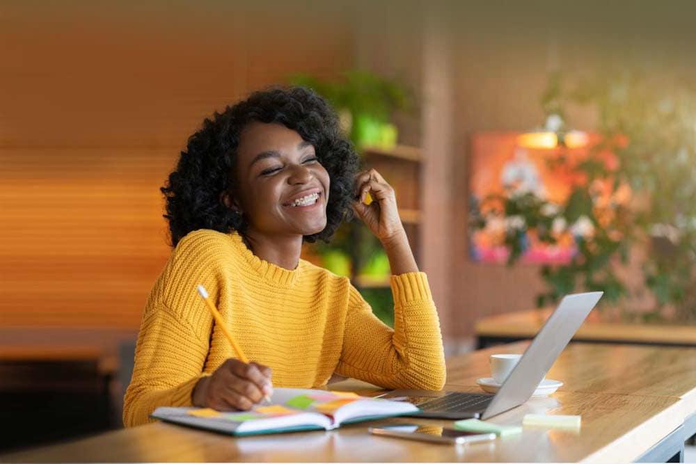 Young girl in a yellow sweater looking at her laptop while taking a class at Washington Connections Academy